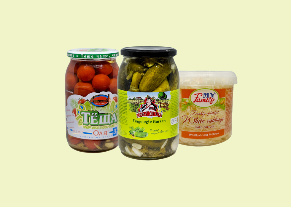 Trois bocaux de légumes marinés : tomates cerises, cornichons, carottes à la coréenne — spécialités de l'épicerie russe